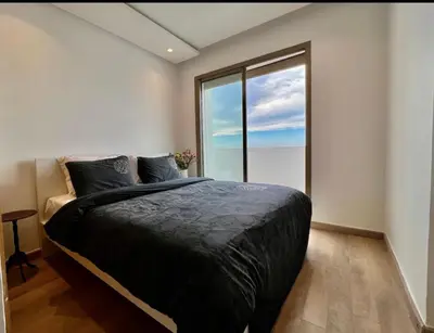 a bedroom with a large bed and a large window at Luxurious Sea View 2 Bedroom Apartment in Anfa