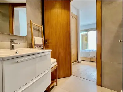 a bathroom with a sink and a mirror and a bedroom at Luxurious Sea View 2 Bedroom Apartment in Anfa