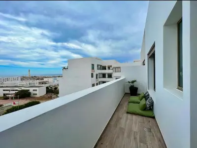 a balcony with white walls and a green couch at Luxurious Sea View 2 Bedroom Apartment in Anfa
