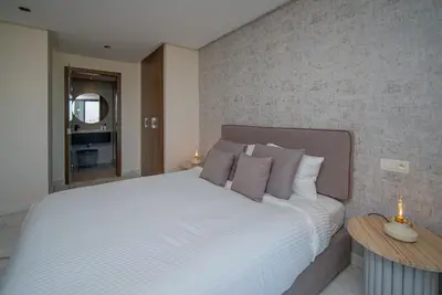 a bedroom with a large white bed with two tables at Luxueux Appartement 2 Chambres, Vue Casa Port in Casablanca
