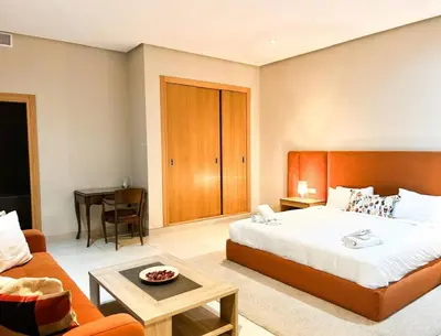 a bedroom with a bed and a couch and a table at Beach Front Apartement With Pool in Casablanca