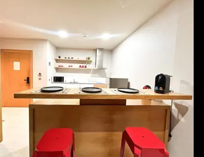 a kitchen with a counter and two red stools at Beach Front Apartement With Pool in Casablanca