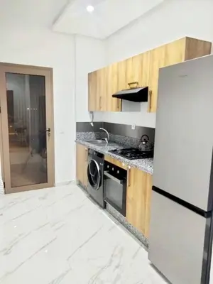 a kitchen with a refrigerator and a dishwasher at Vue mer et parc, terrasse filante in Aïn Harrouda