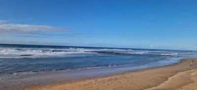 a beach with the ocean and a few people walking on it at Vue mer et parc, terrasse filante in Aïn Harrouda