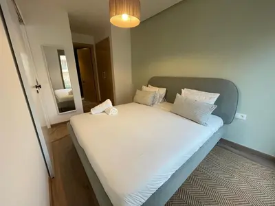 a bed with white sheets and pillows in a room at Charmant studio avec vue sur mer in Rabat