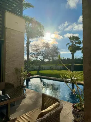 a patio with a pool with chairs and palm trees at Mazagan private villa in El Jadida
