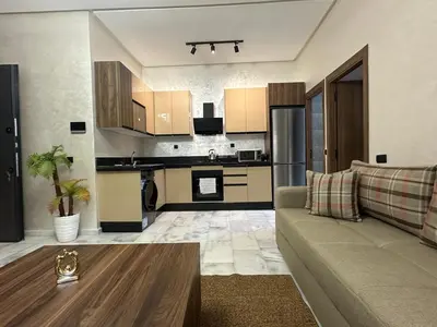 a living room with a couch and a kitchen at Cozy appartement luxueux in Mohammedia