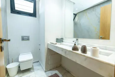 a bathroom with a sink and a toilet and a mirror at Appartement luxueux avec jardin in Rabat