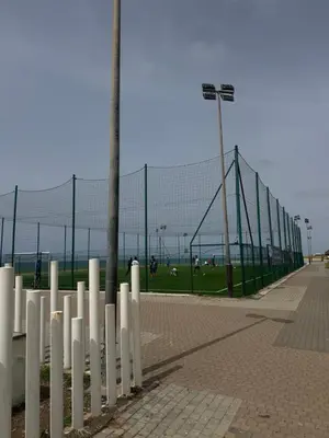 a fence next to a baseball field with people playing at Chill by Sea-Relaxing Stay with a View in Rabat