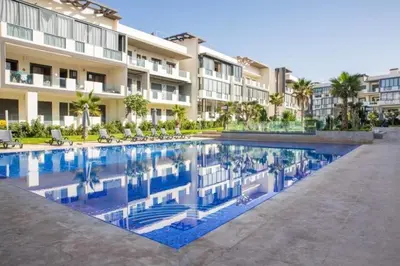 a swimming pool in front of a building at Apartment in Dar Bouazza with Pool, Gym & Kids Playground in Dar Bouazza