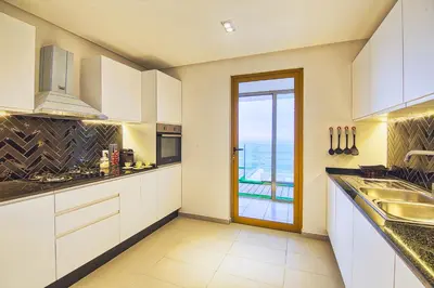 a kitchen with white cabinets and a view of the ocean at BlueVista - Yacht like Escape with Ocean Views in Rabat