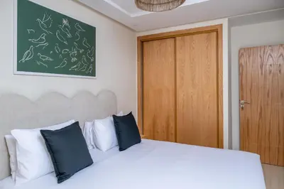 a bedroom with a white bed and a wooden door at Charming Cozy apartments with terrace, Haut Agdal in Rabat