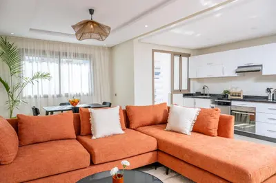 a living room with an orange couch and a kitchen at Charming Cozy apartments with terrace, Haut Agdal in Rabat