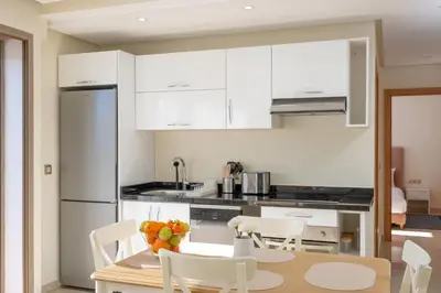 a kitchen with white cabinets and a table and chairs at Charming Cozy apartments with terrace, Haut Agdal in Rabat