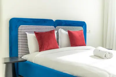 a blue and white bed with red pillows at The lodge Residence by Goodmove - Hay Riad in Rabat