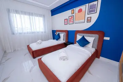 two beds in a room with blue walls at The lodge Residence by Goodmove - Hay Riad in Rabat