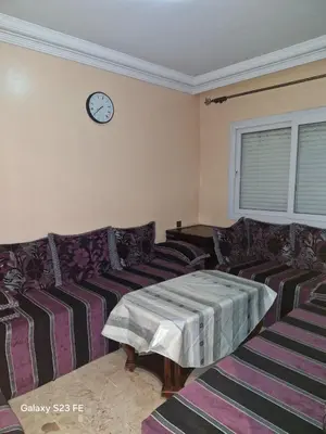 a living room with a couch and a clock on the wall at Baghdad 4 in Aïn Harrouda