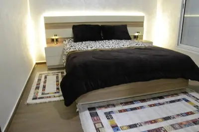 a bedroom with a large black bed with a rug at Bel Appartement à louer à Mansouria in Pont Blondin