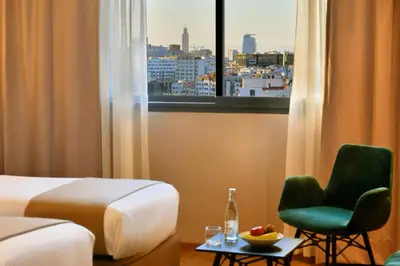 a hotel room with a bed and a chair and a window at ADAY Hotel Casablanca in Casablanca