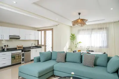 a living room with a blue couch and a kitchen at Very Charming Apartments with balcony, Haut Agdal in Rabat