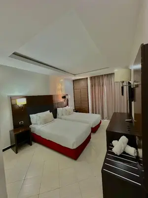 a hotel room with two beds and a desk at Oscar Hotel in Rabat