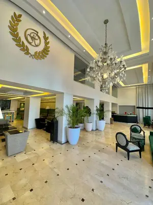 a large lobby with a chandelier and tables and chairs at Oscar Hotel in Rabat