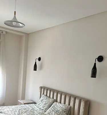 a bedroom with a bed and two lights on the wall at Appartement haut standing Mohammedia Parc in Mohammedia