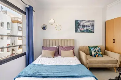 a bedroom with a bed and a couch and a window at Cozy studio moderne Agdal in Rabat