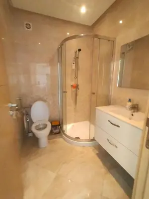 a bathroom with a shower and a toilet and a sink at Beautiful apartment with pool & beach nearby in Bouznika
