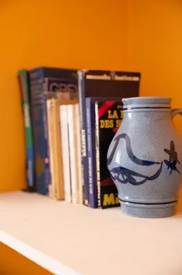 a vase sitting on a shelf with books at Serene 2 BR Apt Steps from Parks & Casa Finance City in Casablanca