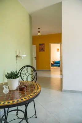 a living room with a table and a chair at Serene 2 BR Apt Steps from Parks & Casa Finance City in Casablanca