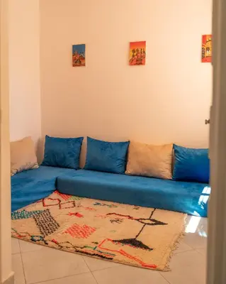 a blue couch in a living room with a rug at Serene 2 BR Apt Steps from Parks & Casa Finance City in Casablanca
