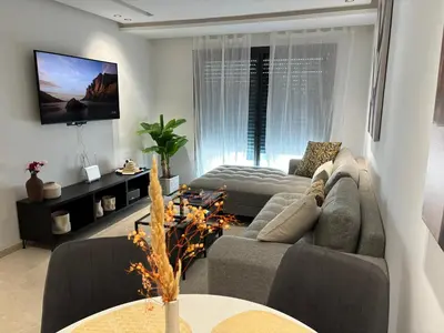a living room with a couch and a tv at Elegance & Comfort - Les Princesses District in Casablanca