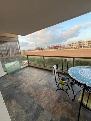 a balcony with a table and a view of a baseball field at Blue beach Sidi Rahal in Le Polo