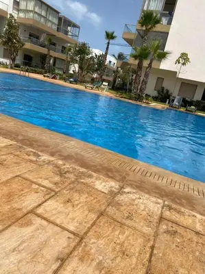 a large blue swimming pool in front of a building at Blue beach Sidi Rahal in Le Polo