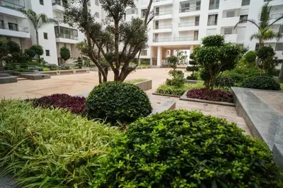 a park with a tree and bushes in front of a building at Ocean Pearl Luxury Stay by Sea in Casablanca