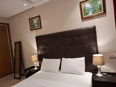 a bedroom with a bed with a black headboard and two lamps at Emma's Luxury Studio 36 in Casablanca