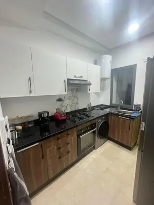 a kitchen with wooden cabinets and a stainless steel appliance at Aymen beach in Mansouria