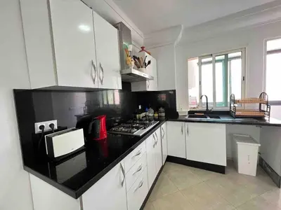 a kitchen with white cabinets and a black counter top at Appt Centre ville Casablanca Maarif avec Terrasse in Casablanca