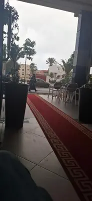 a red rug on a sidewalk with tables and chairs at الهرهورة in Oulad Kerroum