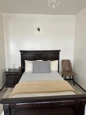 a bedroom with a bed with a wooden headboard and a chair at Emplacement idéal chambre Privée in Rabat