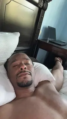 a shirtless man laying on a bed next to a desk at Emplacement idéal chambre Privée in Rabat