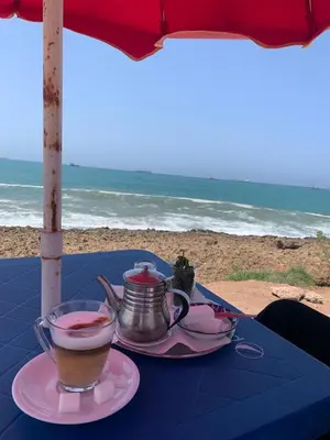 a table with two cups of coffee and a teapot on the beach at Appartement en front de mer à 2 pas des Sablettes in Mohammedia