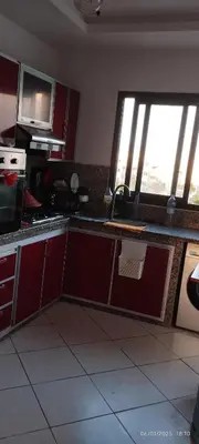 a kitchen with red cabinets and a large window at المنصورية in Mohammedia
