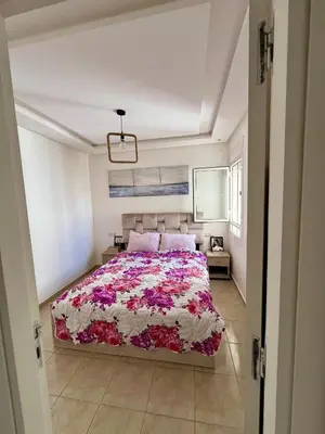 a bedroom with a large bed in a white room at Cosy chambre salon à 2 min harhoura in Temara