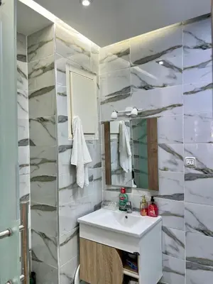 a bathroom with a sink and a marble wall at Cosy chambre salon à 2 min harhoura in Temara