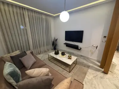 a living room with a couch and a flat screen tv at Cozy studio in ain diab in Casablanca