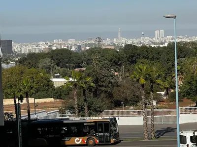 a bus driving down a street with a city in the background at Apartment busway nearshore in Casablanca