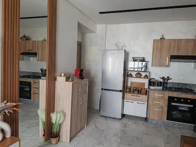 a kitchen with a white refrigerator and wooden cabinets at Beautiful apartment in the heart of Zenata in Aïn Harrouda