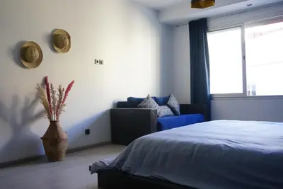 a bedroom with a bed and a couch and a window at Chez vous au cœur de Casablanca in Casablanca